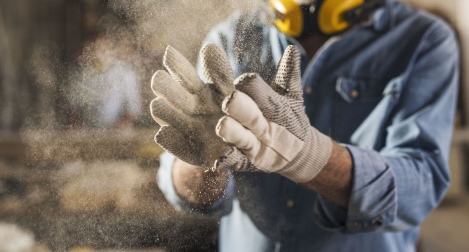 Close up of dusty work gloves Unrecognizable male hands with work gloves on, clapping to remove sawdust